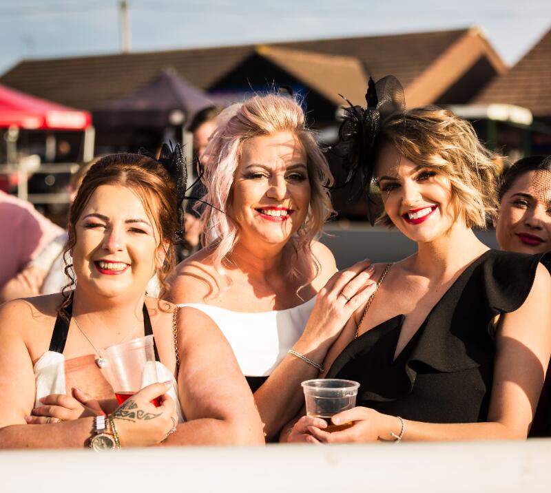A small group of friends pose for a picture at the trackside in the sunshine