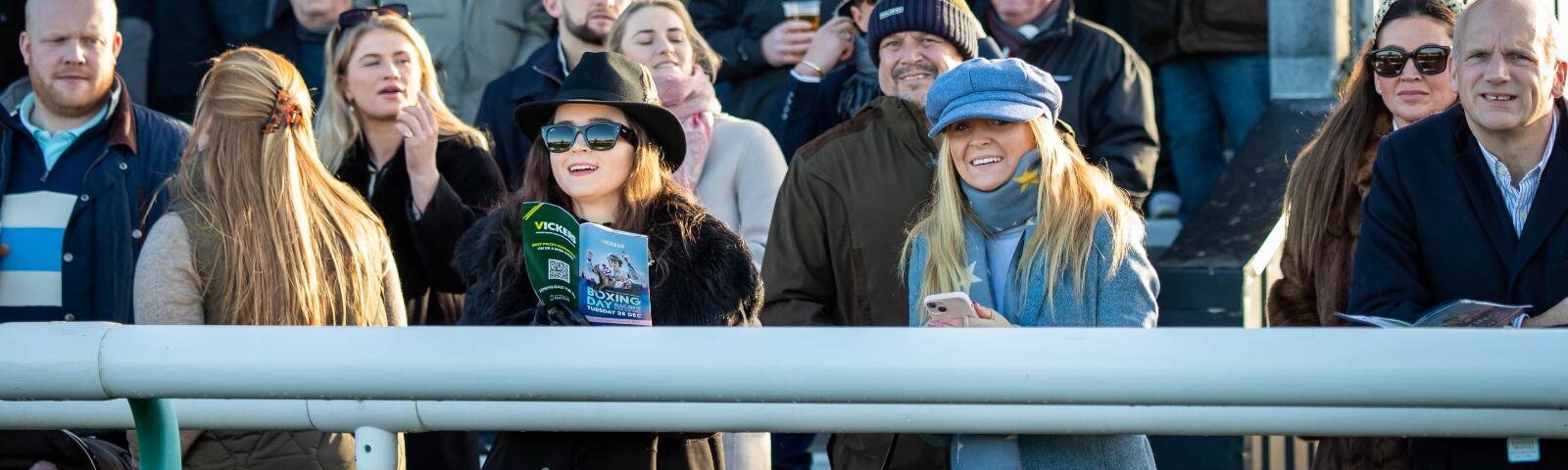 The crowd in the grandstand at Sedgefield, with some race goers holding racecards