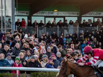The crowd at Sedgefield watching a horse and jockey race by