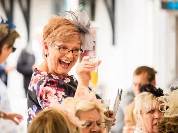 Hospitality guest at Sedgefield Races holding up a glass and smiling