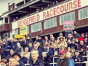 Crowds standing in front of the main grandstand at Sedgefield Racecourse.
