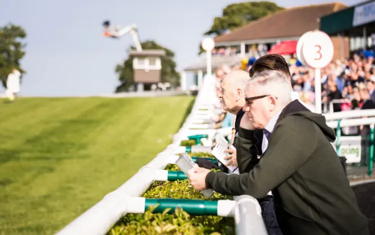A race goer reading a race card at the track side at Sedgefield