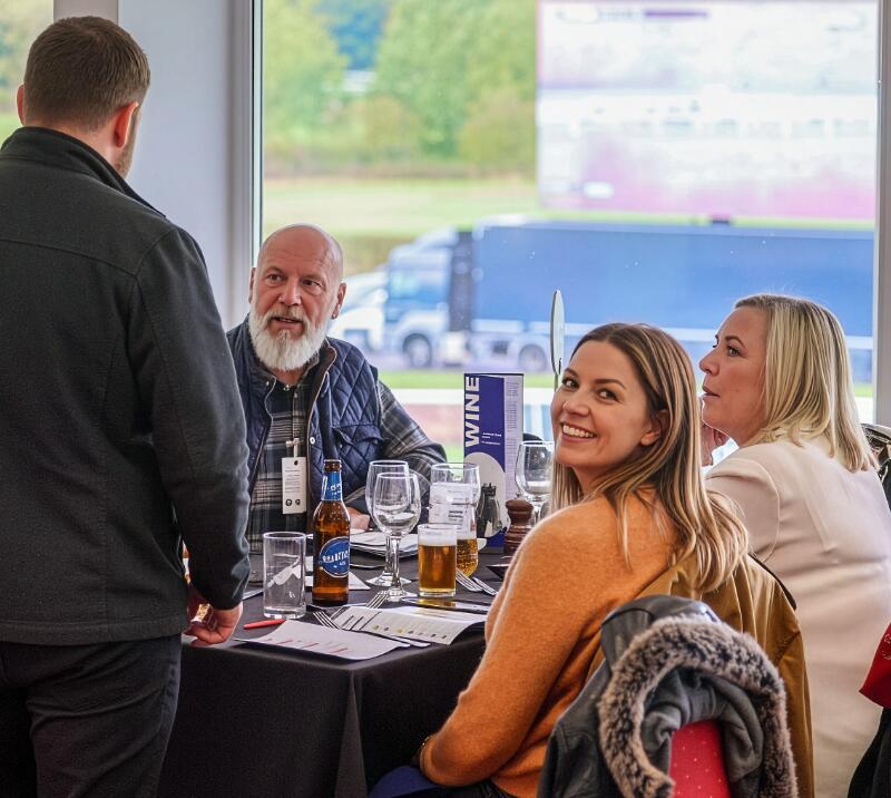 Group of people sitting at a table, with one person smiling for the camera.