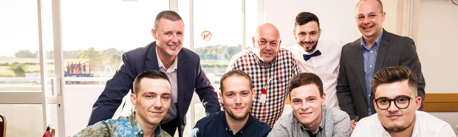 A group of guys at the races pose for a picture in hospitality