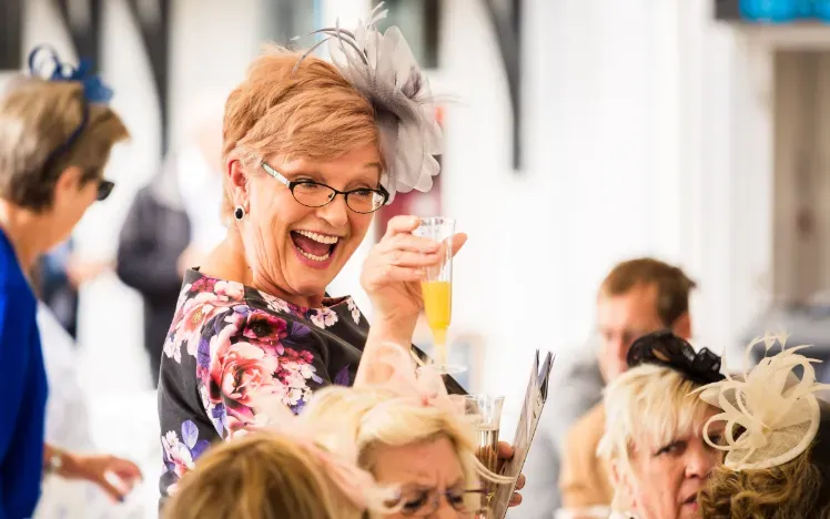 Hospitality guest at Sedgefield Races holding up a glass and smiling