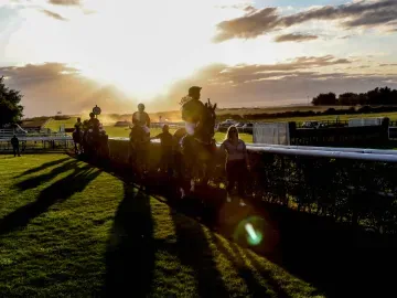 Sunset at Sedgefield Racecourse with horses and jockeys in silhouette 